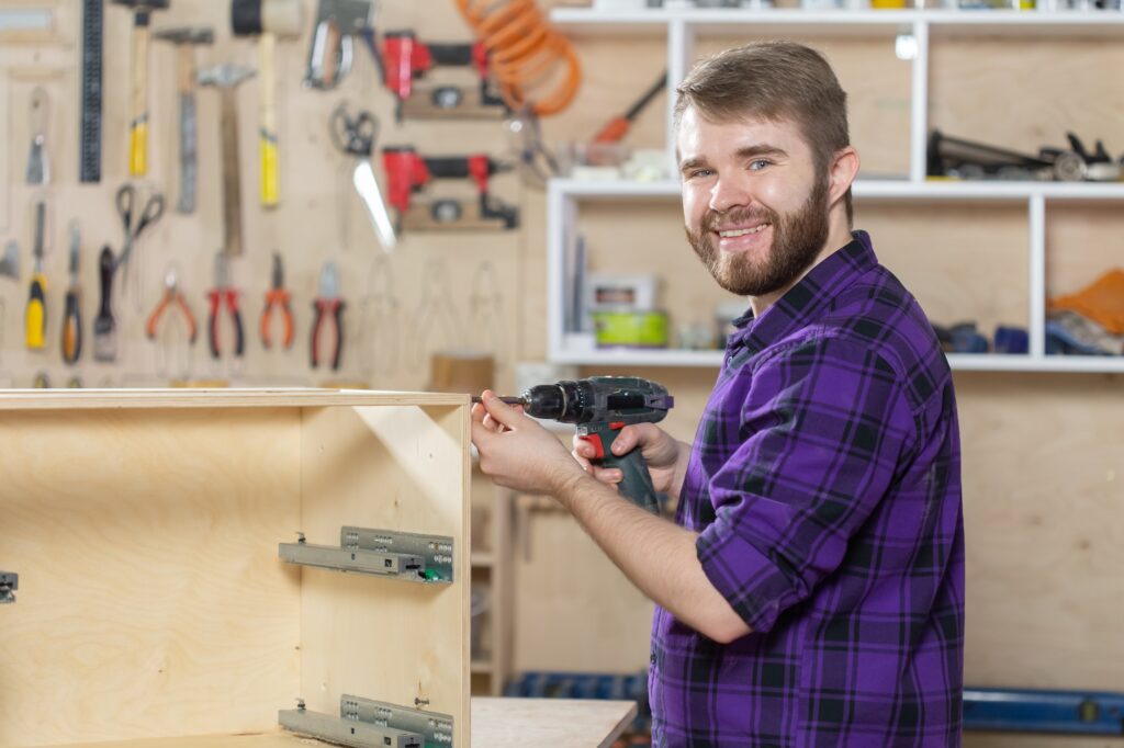 Young bearded man working at the furniture factory